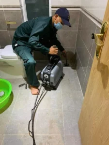 Thợ kỹ thuật thao tác ống hút vào nắp hầm cầu bồn cầu trong nhà vệ sinh